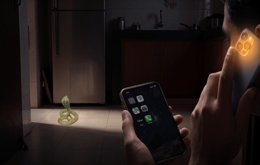 snake-rescue-helpline-vs-consumer-app A cobra in a dark kitchen at night, with one hand fumbling at a cracked phone screen while another holds a phone to the ear